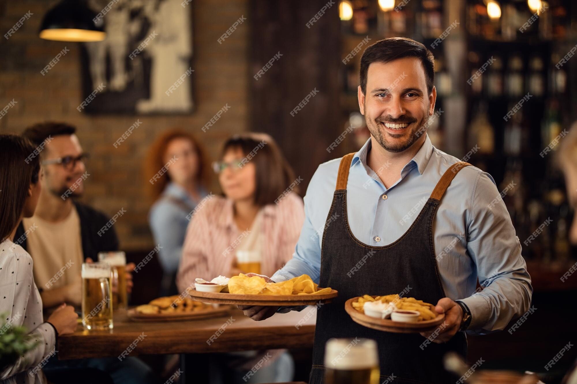 happy-waiter-holding-plates-with-food-looking-camera-while-serving-guests-restaurant_637285-1707